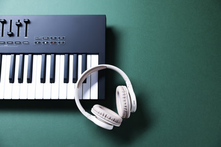 MIDI keyboard and headphones on green background, top view. Space for textの写真素材
