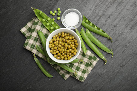 Pickled peas, salt and pods on black table, flat lay