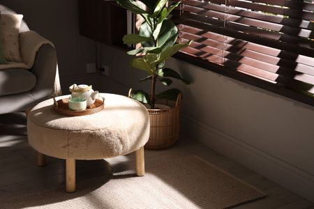 Stylish pouf with tea set in living roomの写真素材