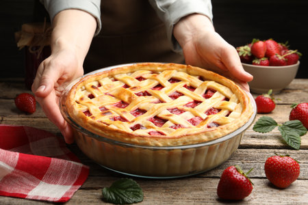 Woman with tasty strawberry pie at wooden table, closeupの写真素材