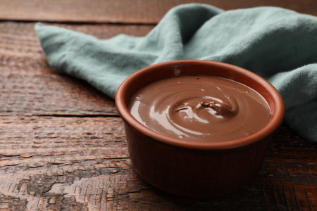Tasty chocolate butter in bowl and napkin on wooden table, closeupの写真素材