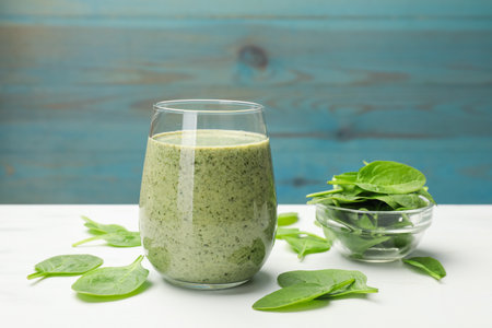 Tasty smoothie and spinach leaves on white marble table, closeupの写真素材