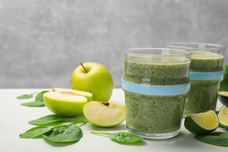 Tasty smoothie and spinach leaves on white table, closeupの写真素材