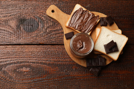 Tasty chocolate butter, pieces and bread on wooden table, top view. Space for textの写真素材