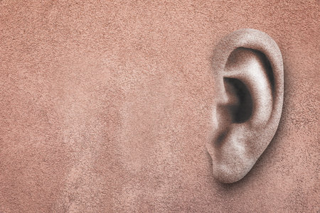 Human ear in pink plaster wall, space for text. Eavesdropping, concept that even walls have ears