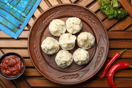Delicious khinkali served with sauce on wooden table, flat layの写真素材