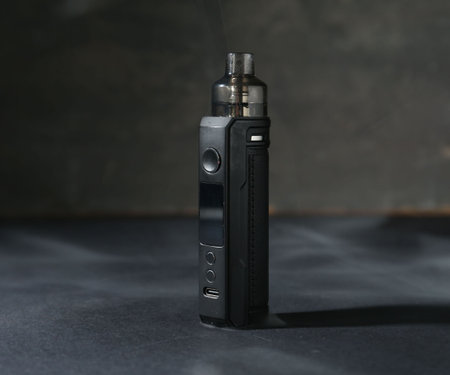 One electronic smoking device on dark table against gray background, closeup