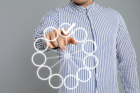 Man putting check mark on virtual screen against gray background, closeupの写真素材