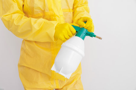 Pest control worker in protective suit spraying insecticide near white wall, closeupの写真素材