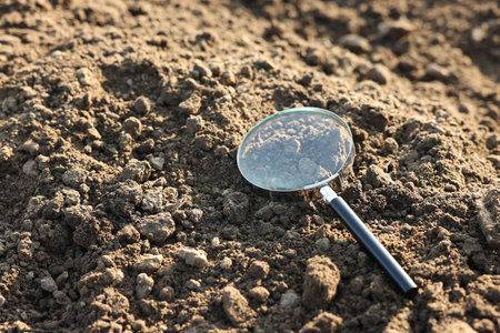 Magnifying glass on dry soil in field, space for textの写真素材