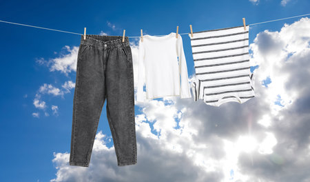 Different clothes drying on washing line against blue sky