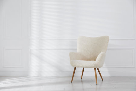 Comfortable beige armchair near white wall indoors, space for textの写真素材