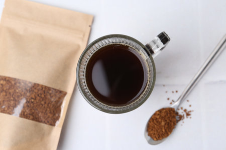 Instant coffee in bag, spoon and cup of drink on light table, flat layの写真素材