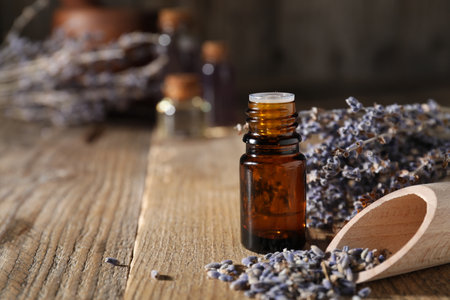 Natural essential oil and lavender flowers on wooden table, closeup. Space for textの写真素材