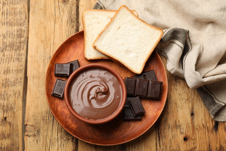 Tasty chocolate butter, pieces and bread on wooden table, top viewの写真素材