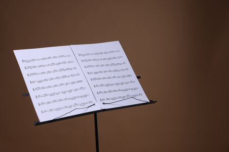 Stand with music sheets on brown background, space for textの写真素材
