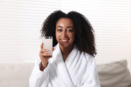 Beautiful Brazilian woman with glass of collagen water indoorsの写真素材