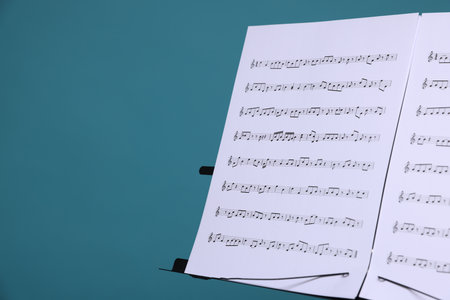 Note stand with music sheets on light blue background, closeup. Space for textの写真素材