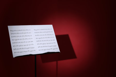 Note stand with music sheets on dark red background, space for textの写真素材