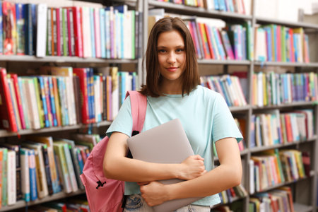 Student with laptop and backpack in library
