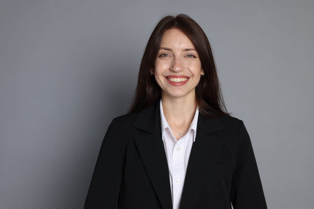 Happy woman in suit on grey background, space for textの写真素材