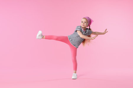 Cute little girl dancing on pink backgroundの写真素材