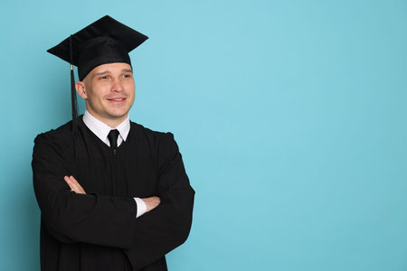 Happy student after graduation on light blue background. Space for text