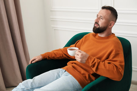 Harmony. Man with tea in armchair at homeの写真素材