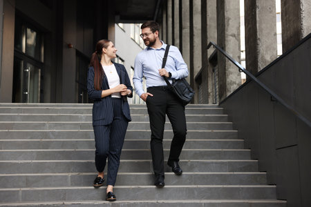 Happy coworkers on stairs near office buildingの写真素材