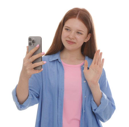 Beautiful teenage girl with smartphone waving hello on white backgroundの写真素材