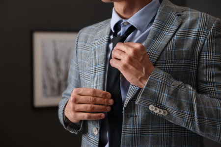 Man tying stylish necktie at home, closeup