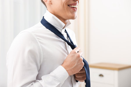 Man tying stylish necktie at home, closeupの写真素材