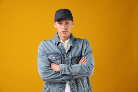 Young man in stylish baseball hat on orange background