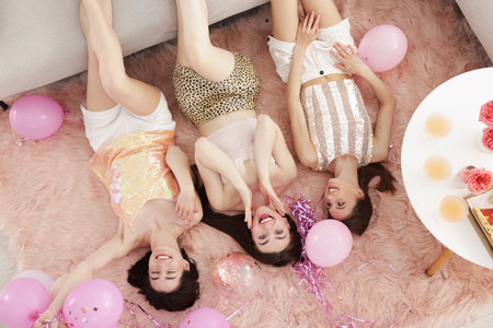 Happy friends with balloons and tinsel on floor at home, top viewの写真素材