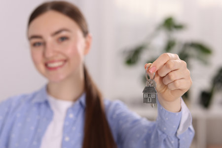 Happy woman with key of her new apartment indoors, selective focusの写真素材