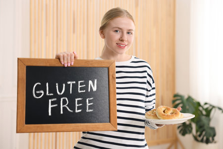 Woman holding small chalkboard with text Gluten Free and pretzels indoorsの写真素材