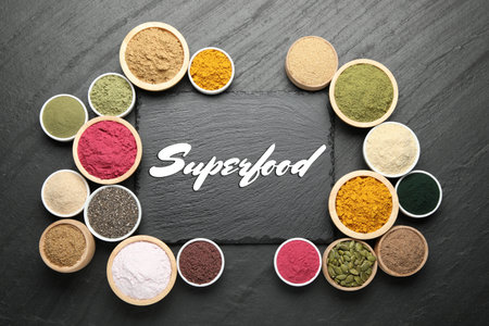 Superfood. Different powders and products in bowls on black table, flat layの写真素材