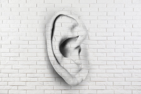 Human ear in white brick wall. Eavesdropping, concept that even walls have earsの写真素材