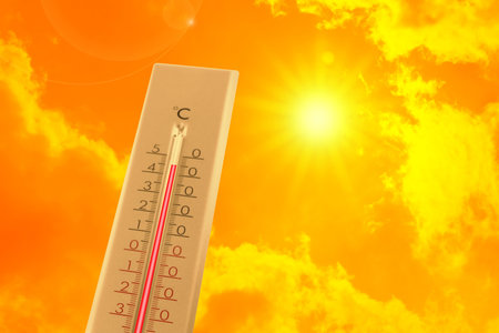 Extremely high temperature on thermometer against orange sky on sunny day. Severely hot summer weatherの写真素材