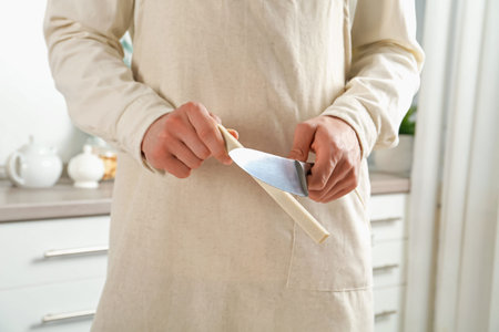Man sharpening knife with sharpener indoors, closeup