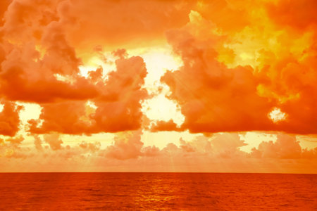 Orange sky with clouds above sea during hot summer weatherの写真素材