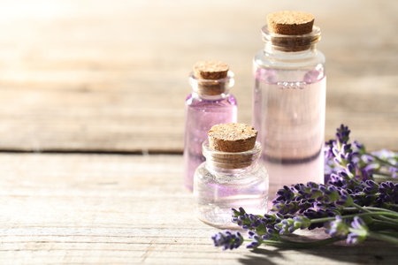 Natural essential oil and lavender flowers on wooden table, closeup. Space for textの写真素材