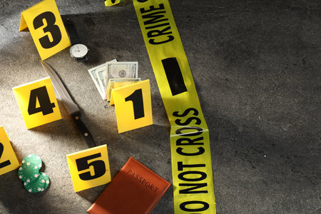 Forensic expert. Yellow crime scene tape, markers and evidence on gray table, above view. Space for textの写真素材