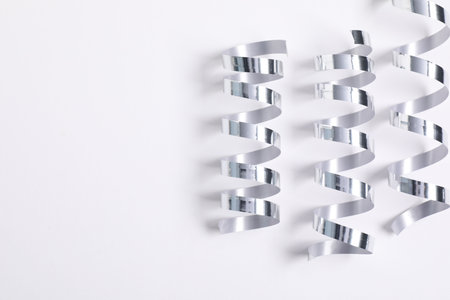 Shiny party streamers on white background, flat lay. Space for textの写真素材