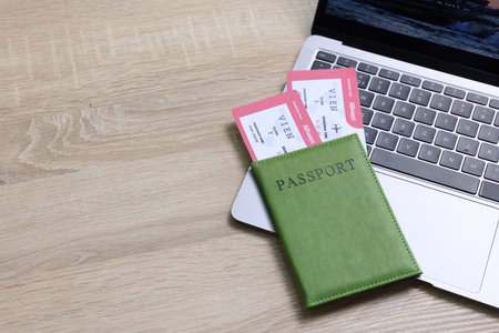 Passport, tickets and laptop on light wooden table, closeup. Space for textの写真素材