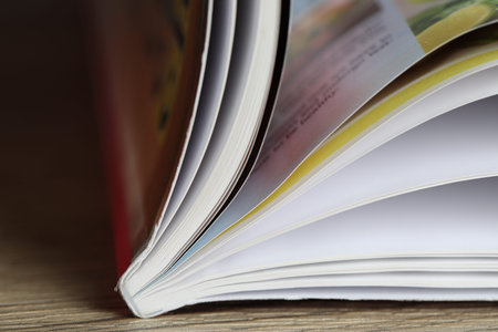 One open magazine on wooden table, closeup