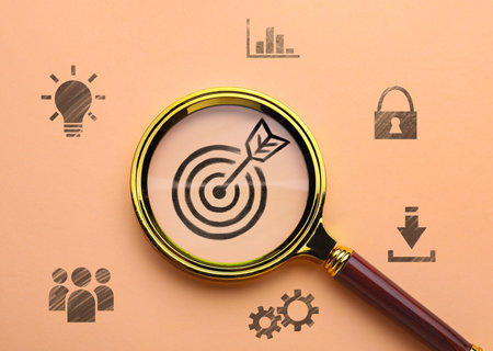 Magnifying glass over target with arrow on pink beige background, top view. Different icons aroundの写真素材