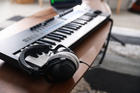 Headphones and MIDI keyboard on wooden table indoors, selective focusの写真素材