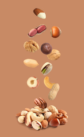 Peanut and other nuts falling on brown backgroundの写真素材