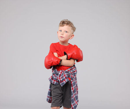 Little boy with boxing gloves on gray backgroundの写真素材